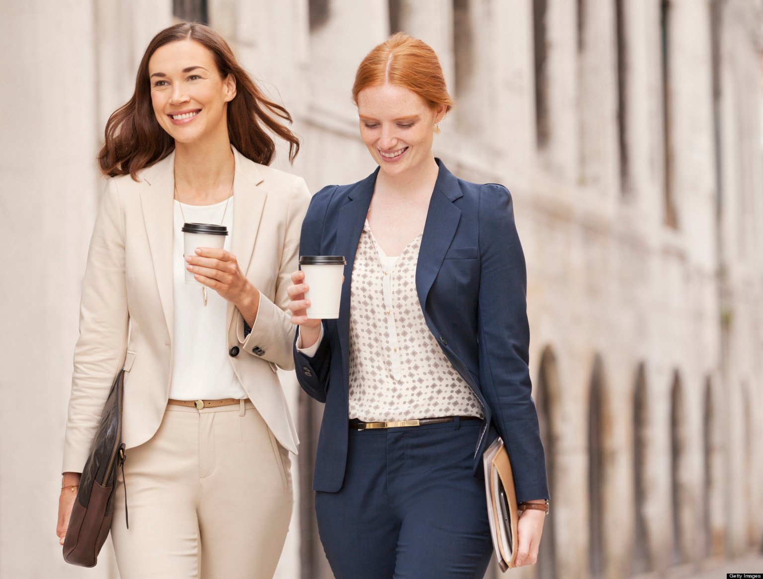 Smiling businesswomen walking with coffee